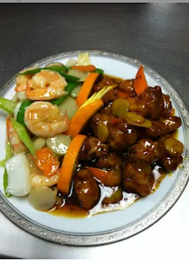 Plate of stir-fried beef in brown sauce with shrimp, peppers, and vegetables on white plate