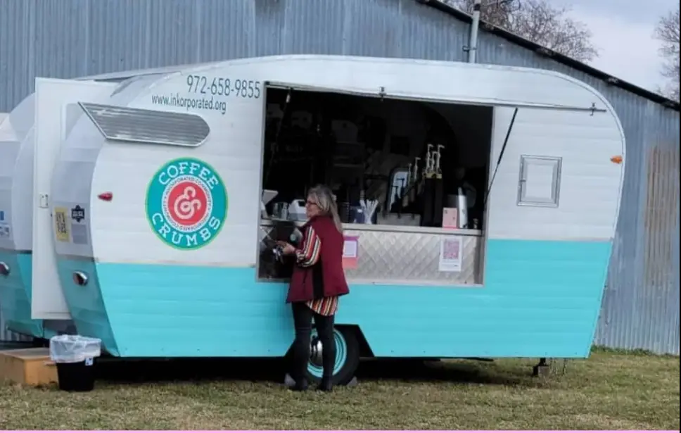 Turquoise and white coffee truck with open service window and customer in maroon shirt ordering at the counter