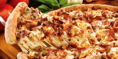 Pizza topped with melted cheese and bacon pieces on wooden surface