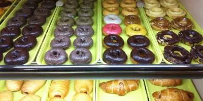 Display case with rows of glazed donuts and pastries in various flavors and colors