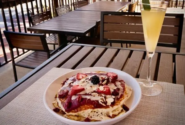 Breakfast pancakes with a strawberry swirl on top and a mimosa on the side
