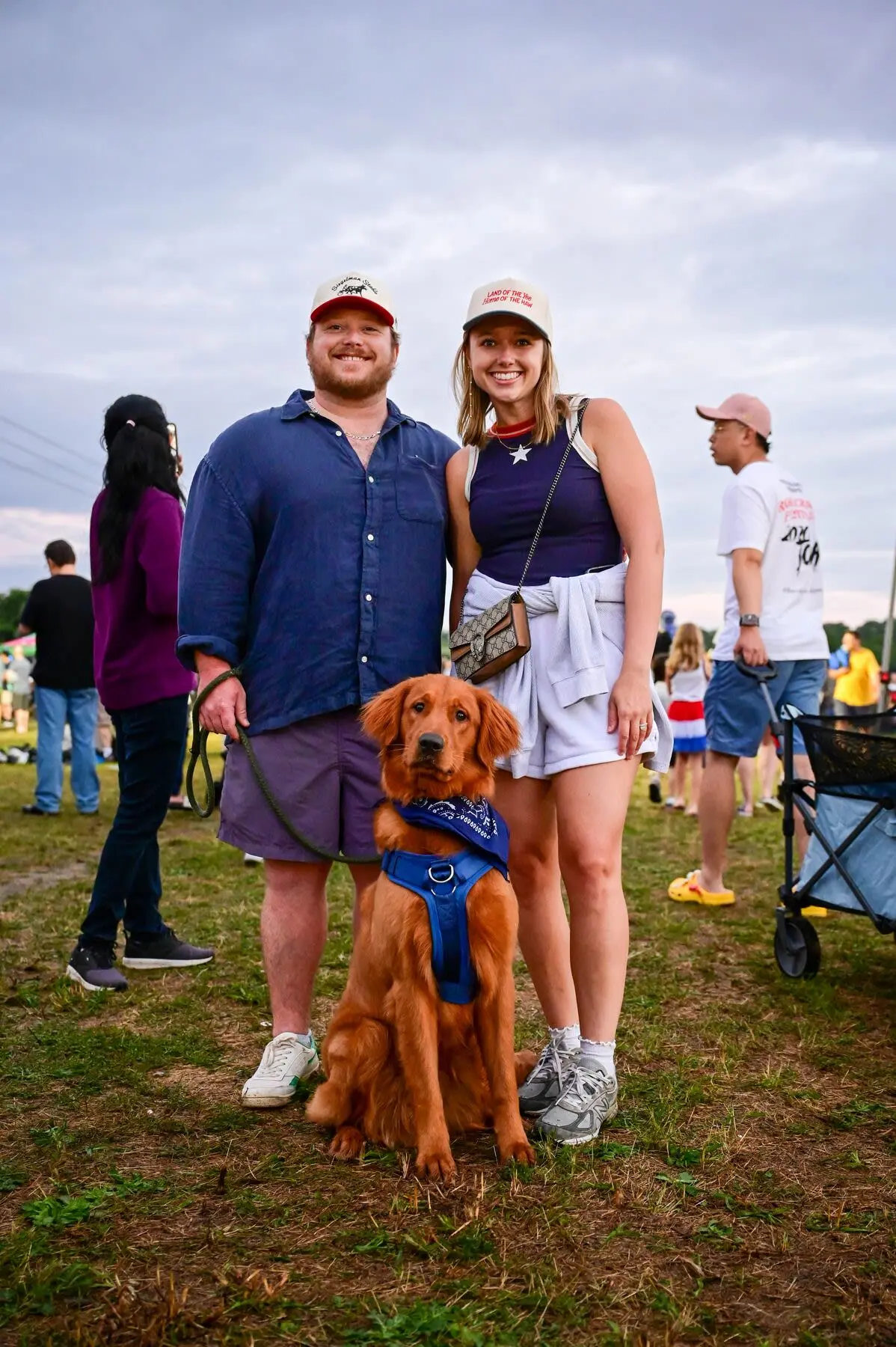 Couple posing with their dog in a field for a July 4th celebration