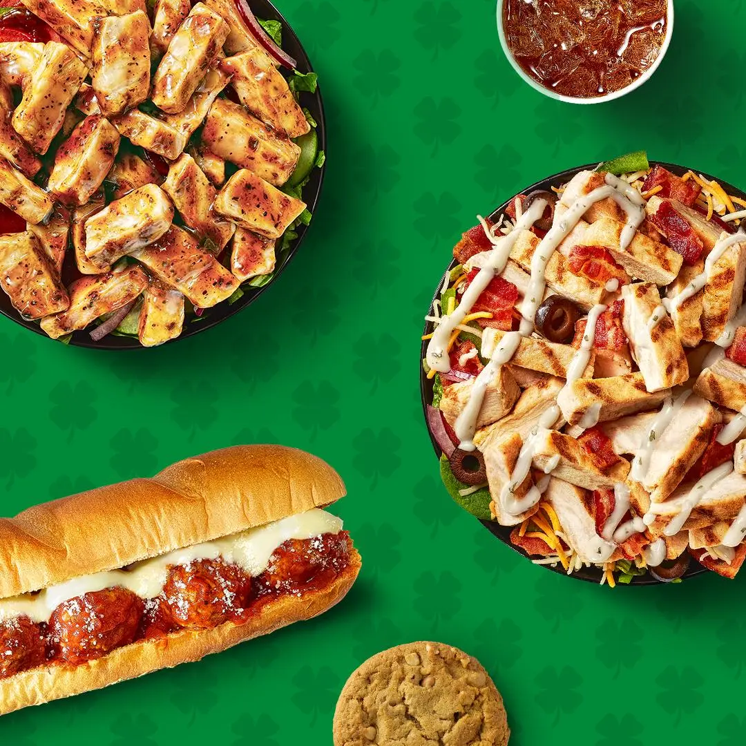 Meatball sub sandwich, loaded nachos with cheese, crispy fries with toppings, and a cookie on green background