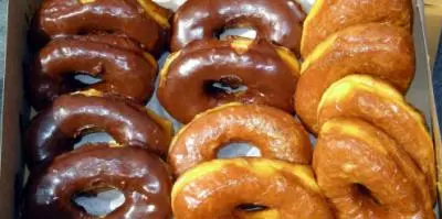 Glazed donuts in chocolate, plain, and honey varieties arranged in a box