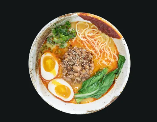 Bowl of ramen with wavy noodles, soft-boiled egg halves, ground meat, green vegetables, and sesame seeds in broth