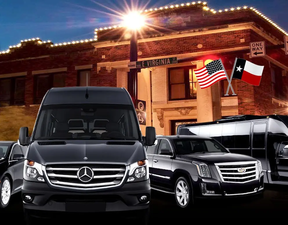 Fleet of luxury vehicles parked in front of brick building at dusk with American and Texas flags displayed