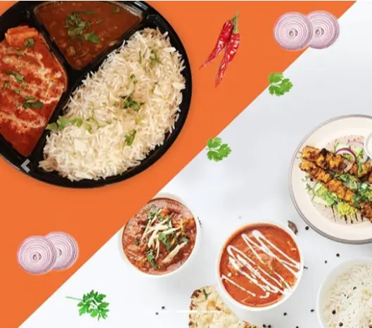 Overhead flatlay of Indian dishes including rice, red curry, tandoori skewers, dipping sauces, fresh cilantro and sliced onions on split orange and white
