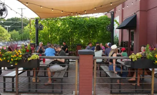 Covered patio with picnic table style seating and people enjoying the nice weather