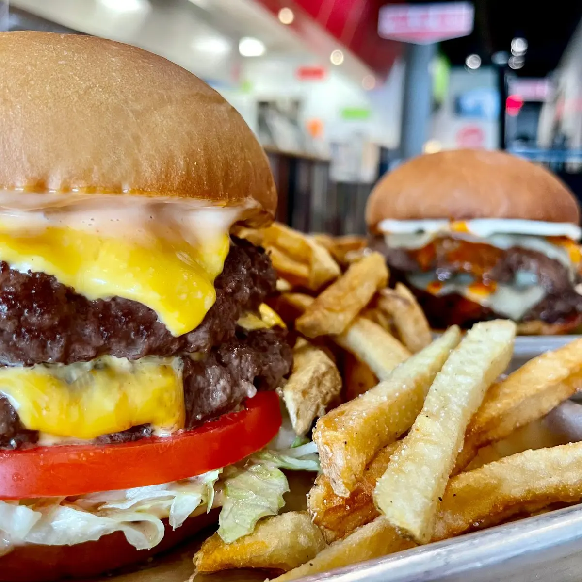Double cheeseburger with tomato and melted cheese on a toasted bun, served with hot French fries