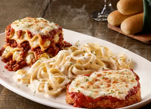 Chicken parmesan with melted cheese and red sauce, served with fettuccine pasta and dinner rolls