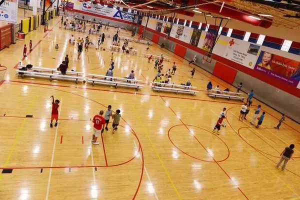 Overhead view of indoor gymnasium with young athletes scattered across wooden court during youth sports practice or training session