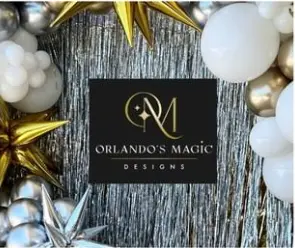 Black business card with gold logo and text on weathered wood surface surrounded by gold and white decorative balloons and ribbons