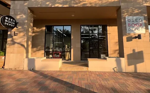 Storefront entrance with glass doors and windows, brick paving, and signage for a used bookstore
