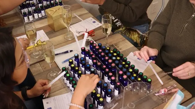 People sitting at a table testing the scent of different bottles