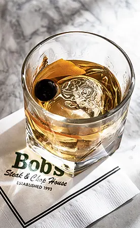 Glass of whiskey with ice on a napkin with restaurant branding