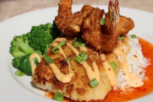 Crispy fried fish fillet with creamy sauce and green onions, served with steamed broccoli, white rice, and red sauce, topped with fried shrimp