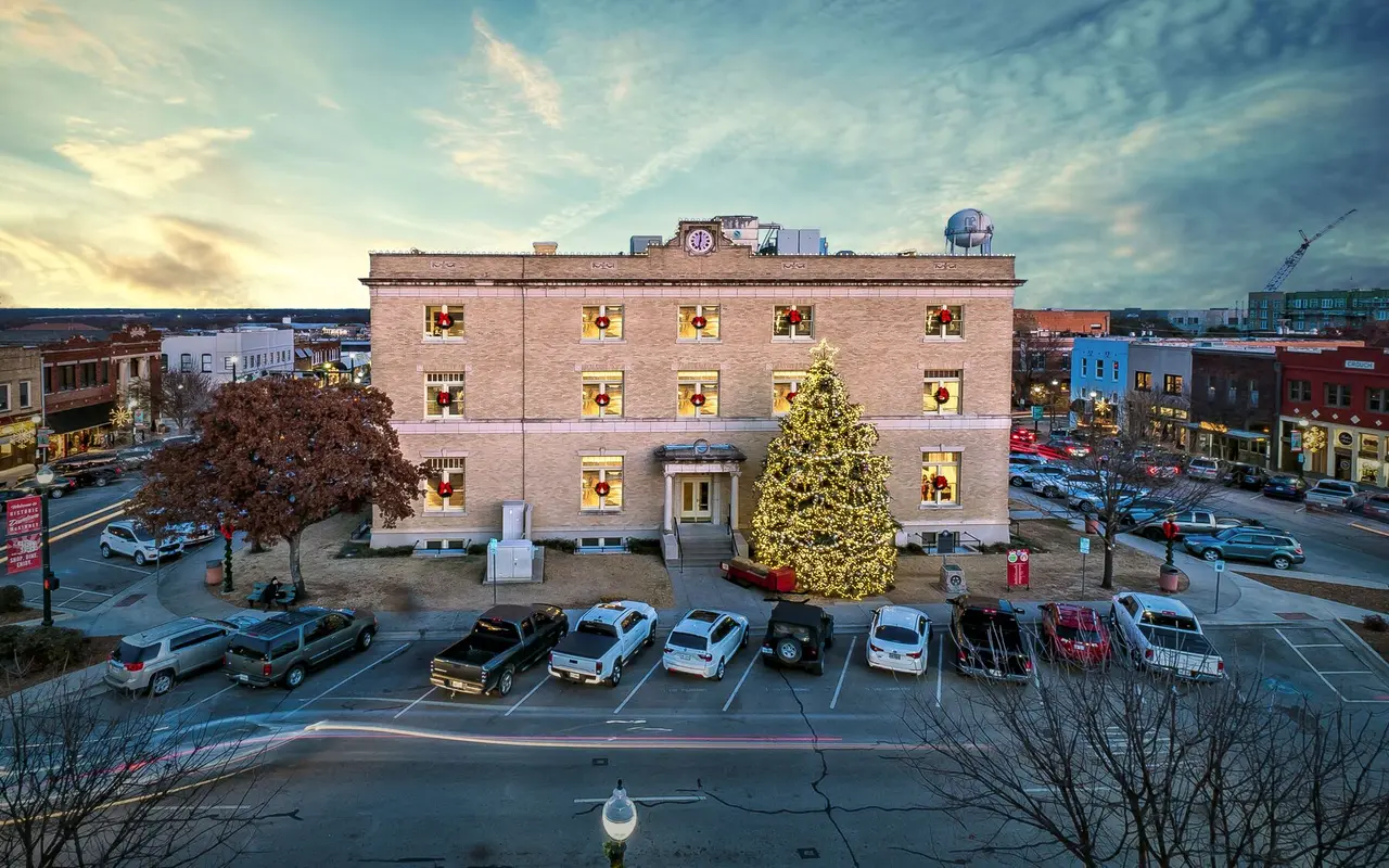 White historic courthouse decorated for a Christmas event with a large Christmas tree outside the building