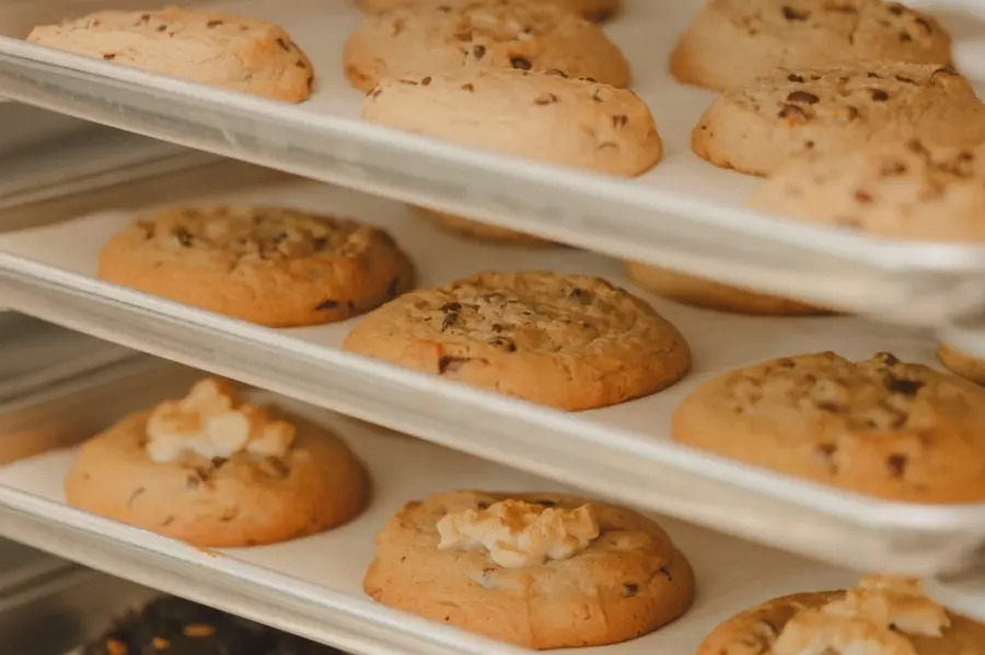 Assorted cookies with chocolate chips and nuts displayed on white tiered shelves
