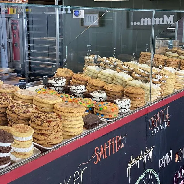 Bakery display window filled with stacked cookies, including sandwich cookies and decorated varieties on tiered shelving