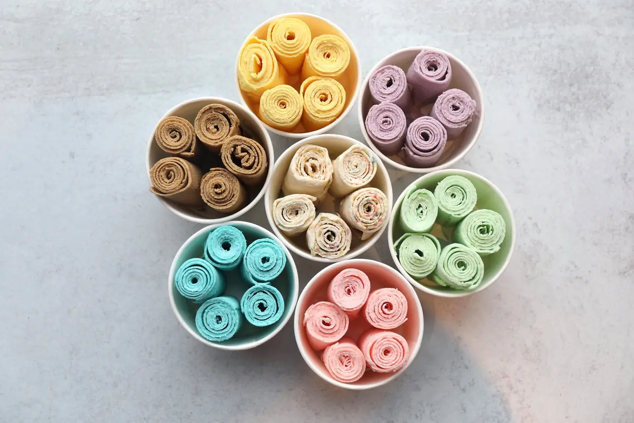 Rolls of colored yarn in white bowls arranged in a circular pattern on a gray surface
