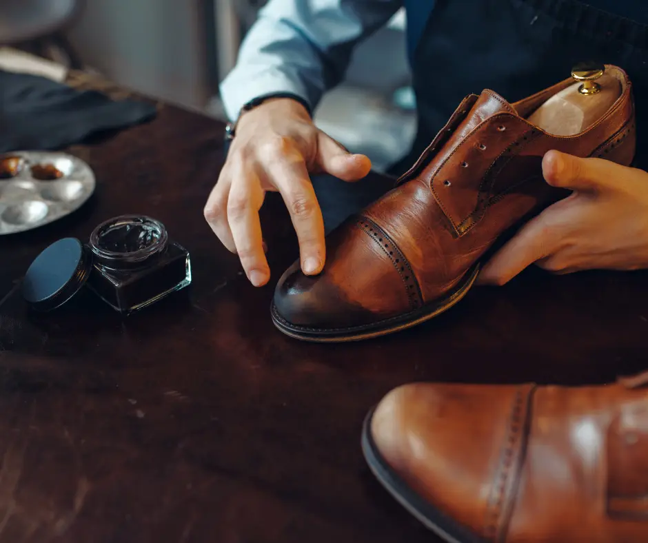 Hands examining a brown leather shoe on a workbench with repair tools nearby