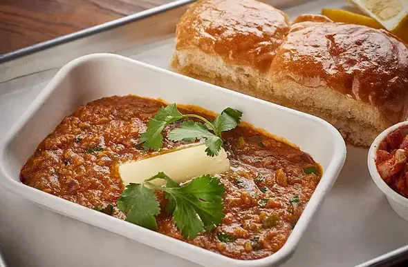 Baked cheese dip with tomato sauce and cilantro garnish, served with crusty bread rolls