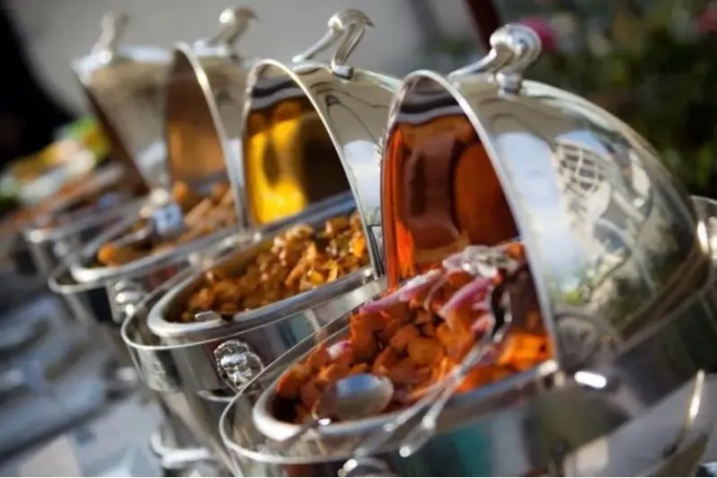 Multiple metal condiment dispensers with various amber and reddish sauces and spices displayed outdoors