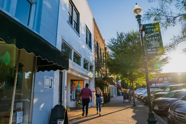 Shops, awnings and a lamppost banner along a historic downtown McKinney street at golden hour