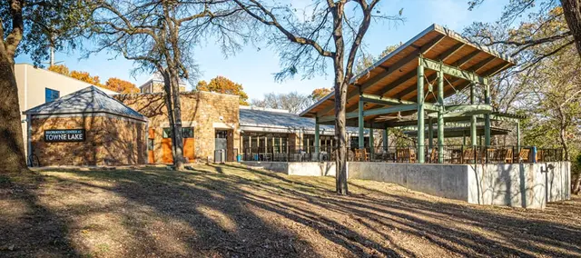 The stone Recreation Center at Towne Lake building and its covered pavilion among oak trees