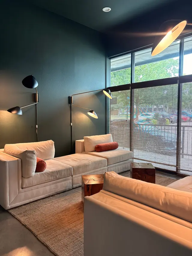 A spa lounge with cream sofas, wall-mounted lamps and a wall of windows onto the street
