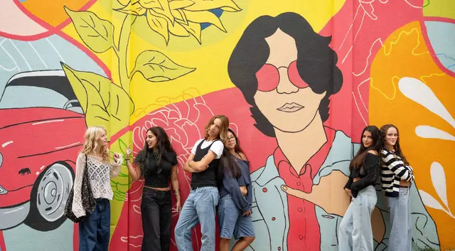 A group in front of a colorful mural in McKinney