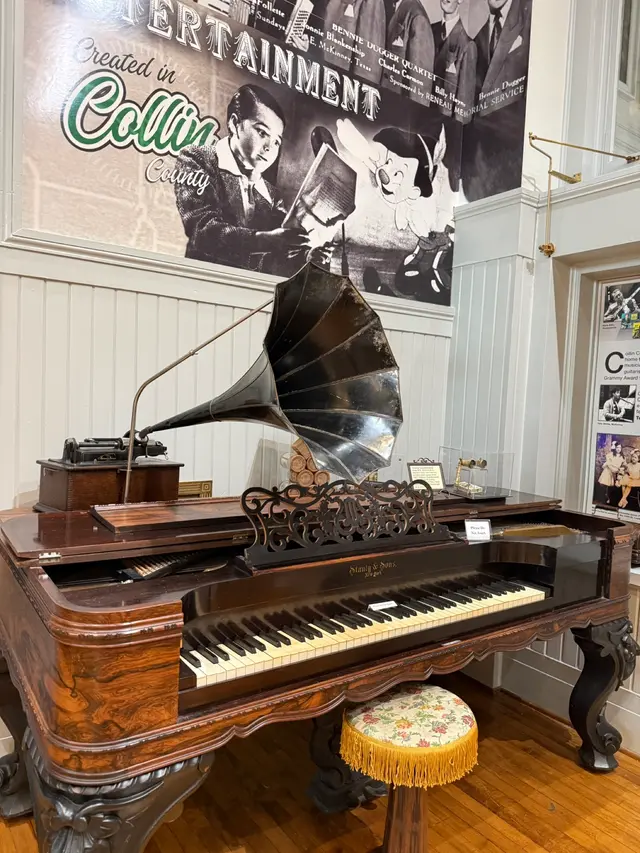 A square grand piano and a phonograph under the Created in Collin County entertainment exhibit