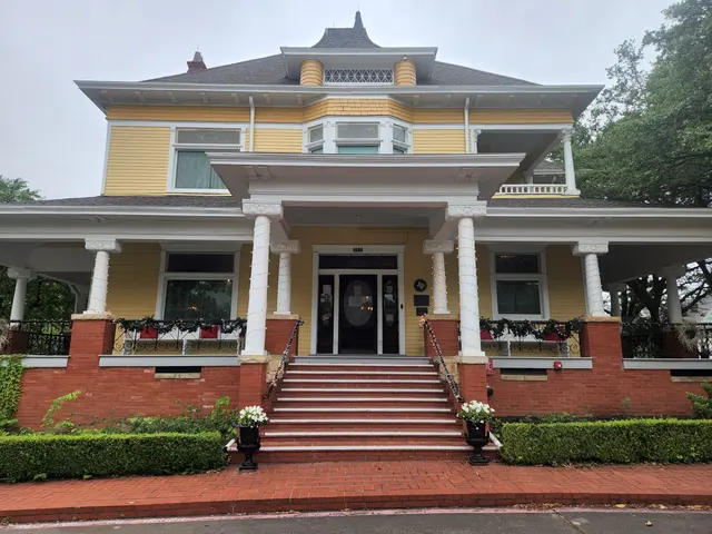The yellow 1900 Heard-Craig House with its columned porch and brick steps