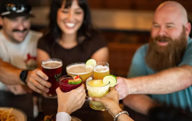 Friends toasting around a long table at a McKinney restaurant
