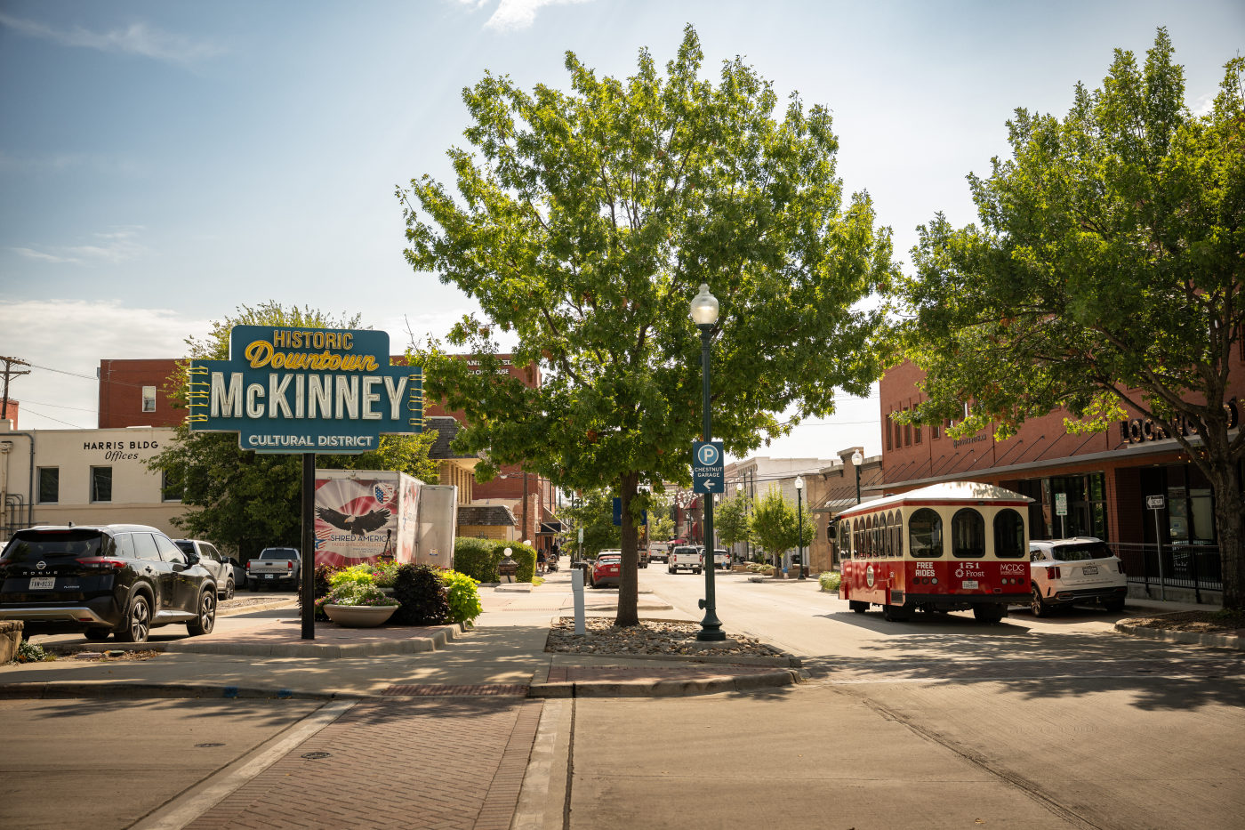 The Historic Downtown McKinney welcome sign with the red and white trolley