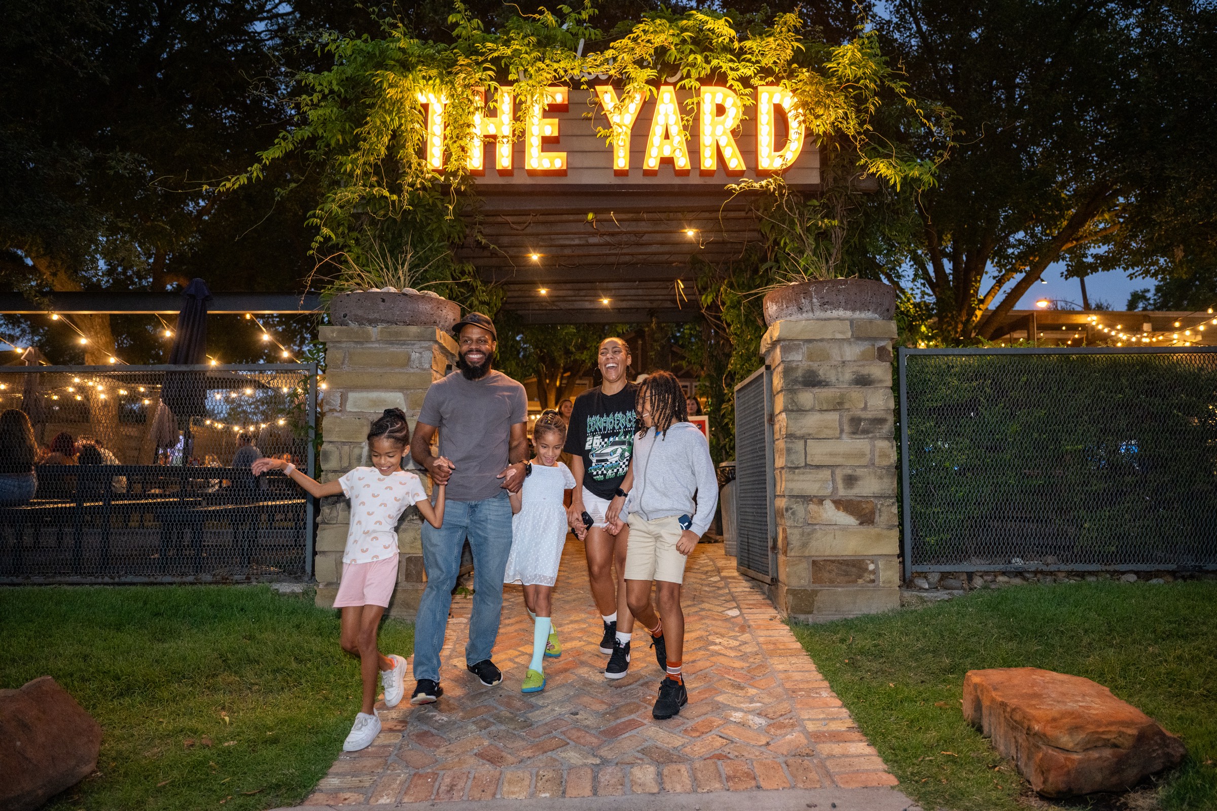 A family walking out under the lit-up sign at The Yard in McKinney